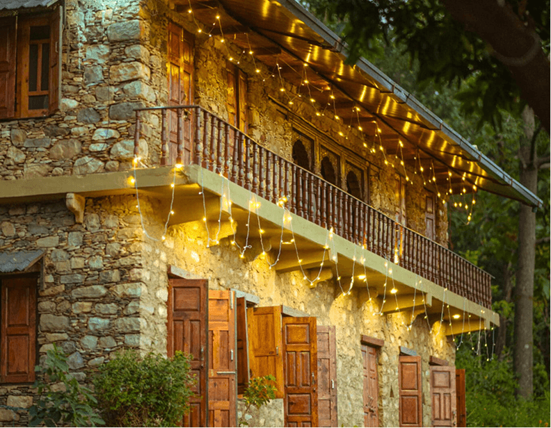 Exterior view of the stone homestay lit with warm lights